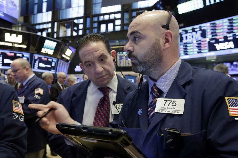 Traders Tommy Kalikas (left) and Fred Demarco work Monday on the floor of the New York Stock Exchange where stock indexes hovered near record levels ahead of a busy week of events that could swing markets, analysts said.