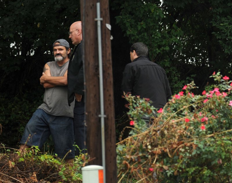 Mark Chumley (left) of Fayetteville speaks with Cpl. Robin Fields on Aug. 19, 2015, outside a house at 455 S. Hill Ave. after a caller reported a death at the residence. Chumley, 47, is charged with accomplice to capital murder in the killing of Victoria Annabeth Davis.