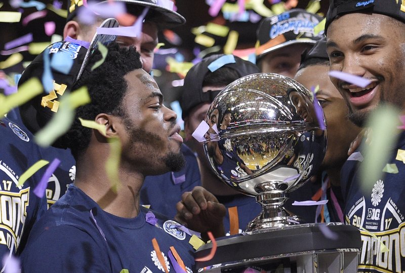 Michigan's Derrick Walton Jr., left, looks at the trophy as he and teammates celebrate after defeating Wisconsin 71-56 in an NCAA college basketball game for the Big Ten tournament title, Sunday, March 12, 2017, in Washington. (AP Photo/Nick Wass)