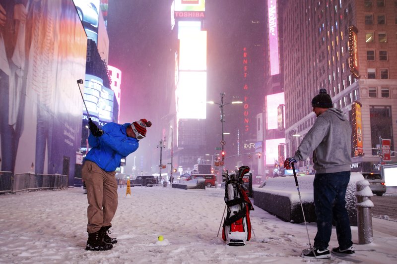 Two men play golf with a tennis ball as a snowstorm sweeps through Times Square, Tuesday, March 14, 2017, in New York. (AP Photo/Mark Lennihan)
