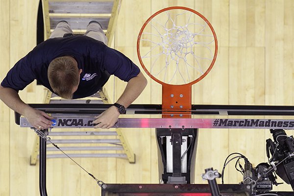 A worker adds decal to the top of a backboard in preparation for the NCAA college basketball tournament, Thursday, March 20, 2014, in San Antonio. (AP Photo/Eric Gay)

