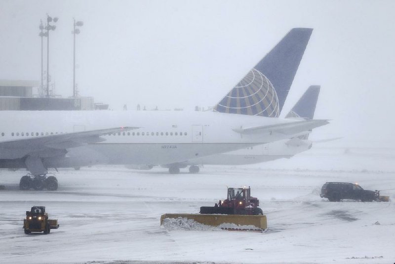 Snowplows work on the tarmac at Newark Liberty International Airport in New Jersey on Tuesday. Flights were canceled at airports across the Northeast.  