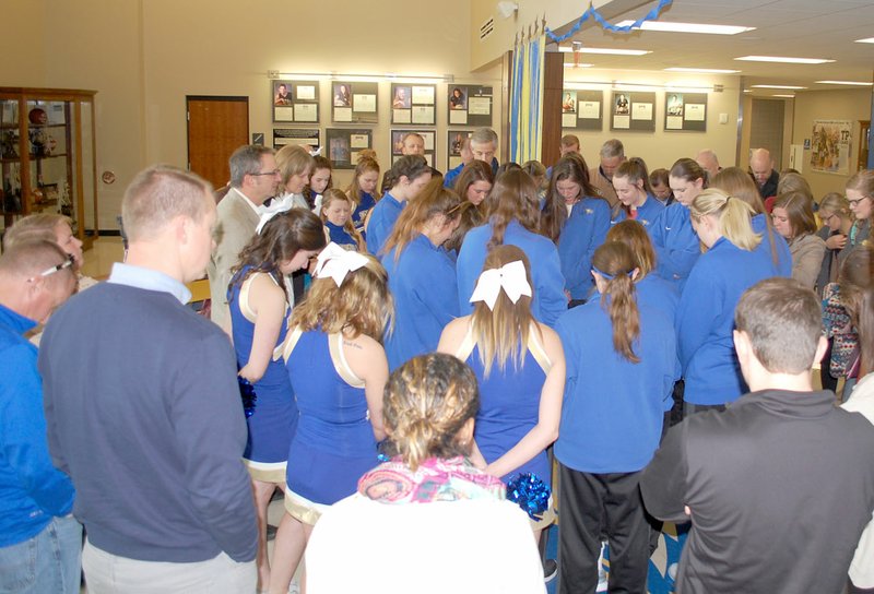 Graham Thomas/Herald-Leader Supporters of the John Brown University women&#8217;s basketball team gather around the players on Monday morning for a prayer led by Vice President Steve Beers just before the Golden Eagles departed for XNA for their flight to Billings, Mont., the site of the NAIA Division I National Tournament.