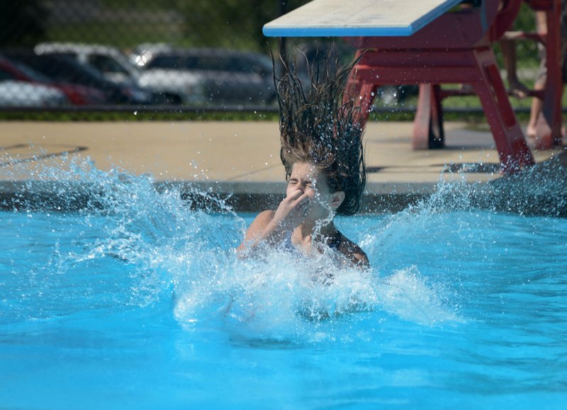 NWA Democrat-Gazette/File Photo A swimmer makes a splash last summer while taking turns on the diving board at the Melvin Ford Aquatic Center in Bentonville.