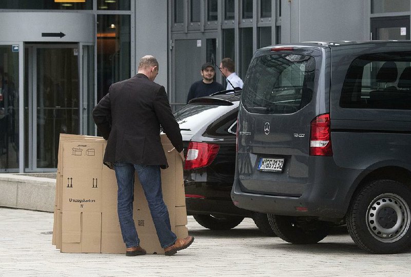 An investigator carries cardboard cartons in front of the Audi headquarters in Ingolstadt, Germany, during a search there Wednesday. 