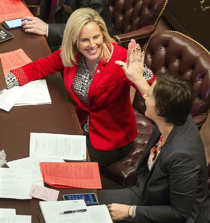 Rep. Jana Della Rosa, R-Rogers, (bottom) congratulates Rep. DeAnn Vaught, R-Horatio, after a unanimous vote in the House for Vaught’s bill to raise the state maximum speed limit to 75 mph. 