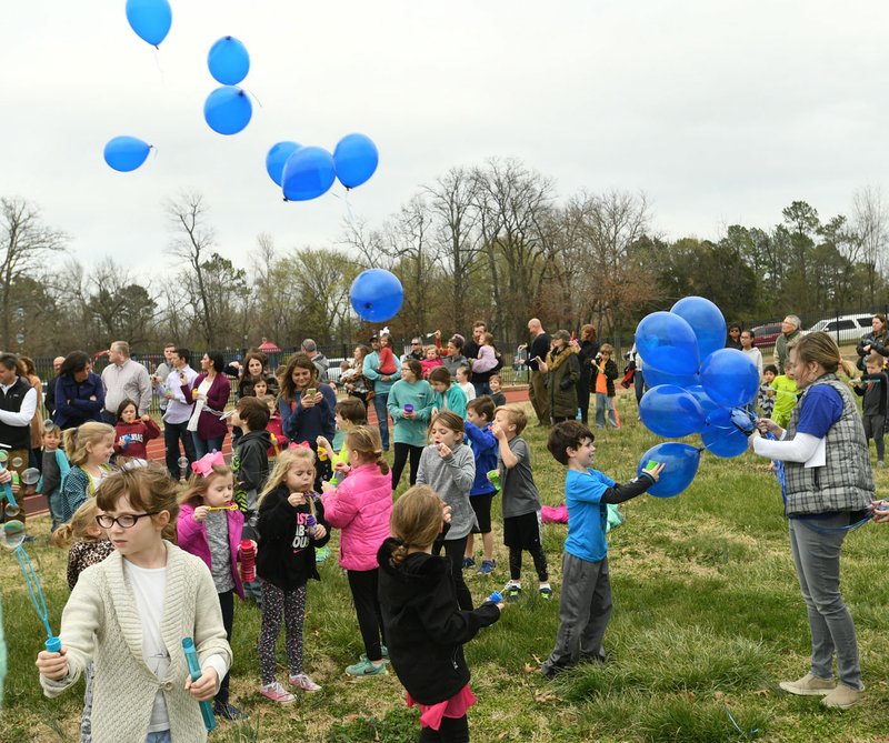 NWA Democrat-Gazette/ANDY SHUPE Wanda Baker (left), 8, a second-grader at Vandergriff Elementary School, holds a bubble wand in the wind Thursday while taking part in a balloon release at the Bob Kraynik Community Sports Complex at the school in Fayetteville. The event was held in remembrance and celebration of Adron Benton, a 6-year-old student at Vandergriff who was found in a nearby swimming pool March 7 and later died.