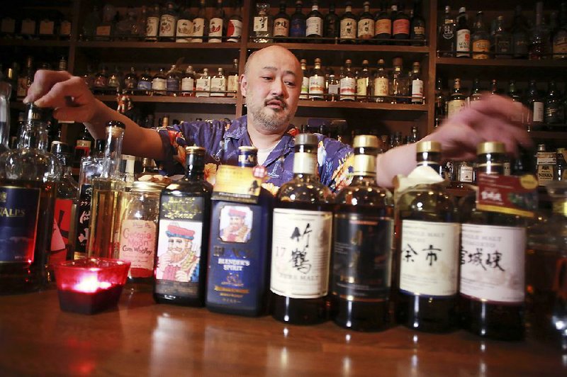 Shot bar Zoetrope’s owner and bartender Atsushi Horigami adjusts the bottles of Japan-made whisky at his bar in Tokyo.