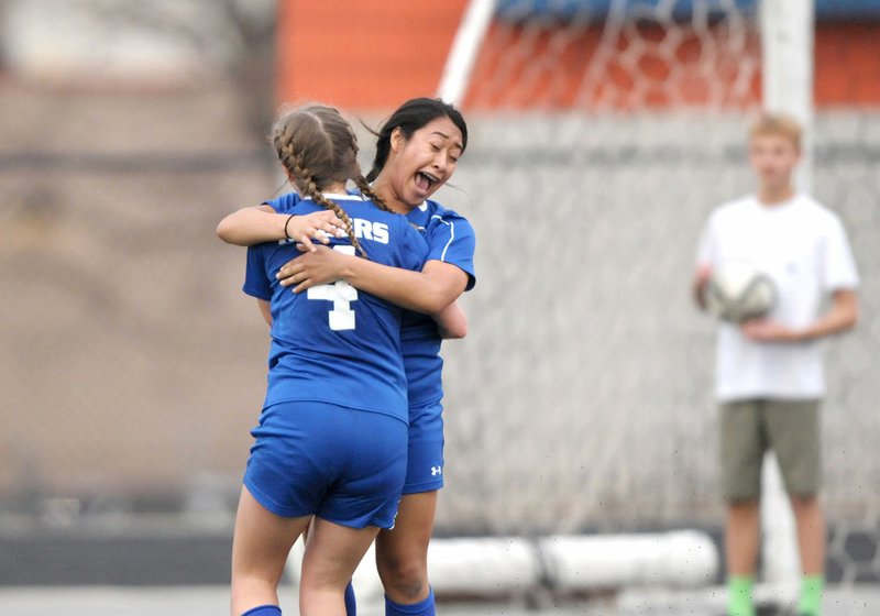 Rogers High’s Leslie Barrales (2) hugs teammate Haley Arrick (4) on Friday after scoring a goal against Rogers Heritage at Gates Stadium in Rogers.