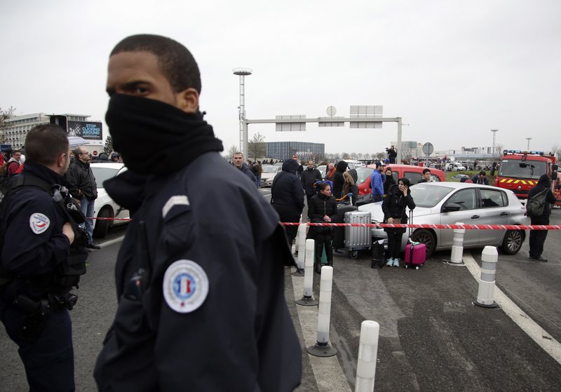 A French police officer guards travelers waiting outside the Orly airport , south of Paris, Saturday, March, 18, 2017. A man was shot dead after wrestling a soldier to the ground at Paris' Orly Airport and trying to take her rifle, officials said.