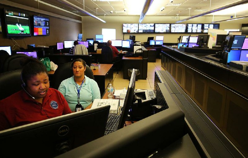 Call-taker Kendra Williams (left) trains new employee April Staggers on Thursday at the Little Rock 911 Communications Center. A shortage of trainers is one of many factors contributing to understaffing problems at the center, city officials said. 