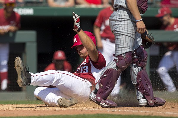 Arkansas' Jordan McFarland slides past Mississippi State catcher Dustin Skelton Sunday, March 19, 2017, for a run at Baum Stadium in Fayetteville.