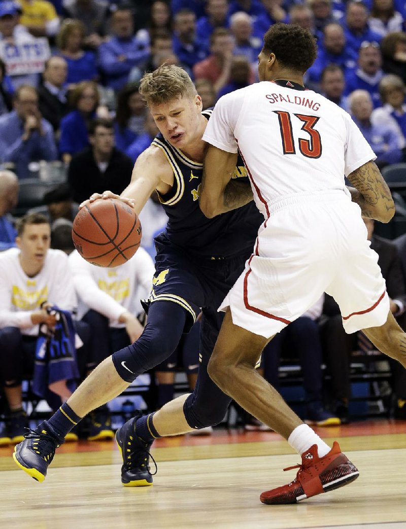 Michigan forward Moe Wagner (left) drives on Louisville forward Ray Spalding (right) in the second half of the Wolverines’ 73-69 victory over the second-seeded Cardinals in the Midwest Regional in Indianapolis, Ind. Wagner had a team-high 26 points.