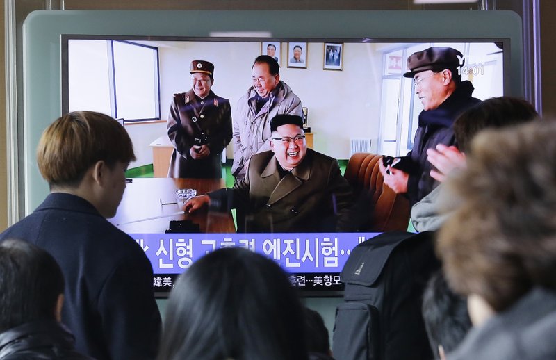 People watch a TV news program showing an image, published in North Korea's Rodong Sinmun newspaper, of North Korean leader Kim Jong Un at the country's Sohae launch site, at Seoul Railway station in Seoul, South Korea, Sunday, March 19, 2017. North Korea has conducted a ground test of a new type of high-thrust rocket engine that leader Kim Jong Un is calling a revolutionary breakthrough for the country's space program. 