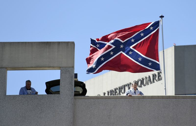 Basketball fans look out as a Confederate flag flies from a parking deck outside the arena before a second-round game of the NCAA men's college basketball tournament in Greenville, S.C., Sunday, March 19, 2017. A small group of protesters flew a large Confederate flag from the top of a parking garage next to the arena hosting two men's NCAA Tournament games. (AP Photo/Rainier Ehrhardt)
