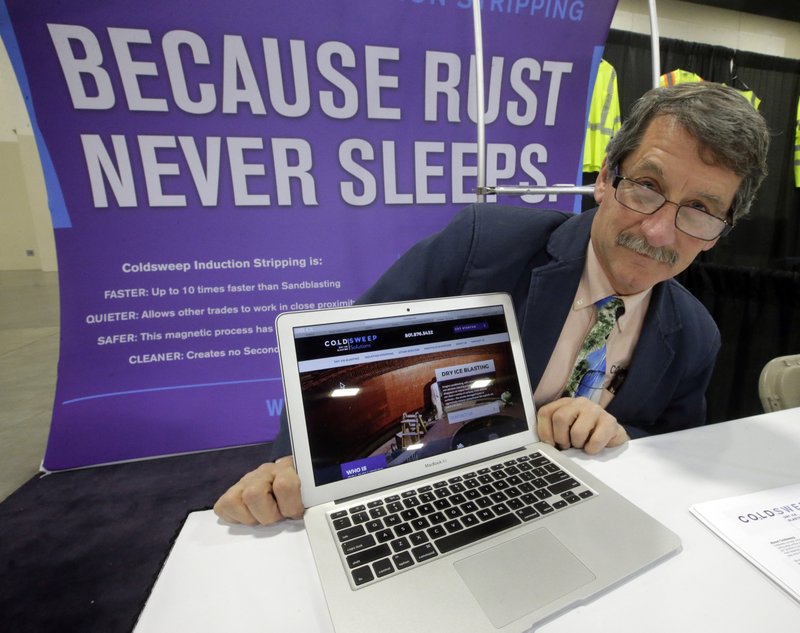 Randell Heath, in Sandy, Utah, poses next to a laptop displaying his company’s website.
