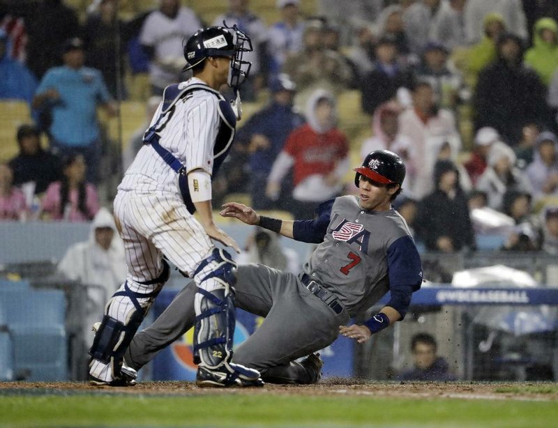 United States base runner Christian Yelich (right) slides into home past Japan catcher Seiji Kobayashi in the fourth inning of Tuesday night’s game in the World Baseball Classic. The Americans held on to win 2-1 and advance to today’s championship game against Puerto Rico, which beat the Netherlands 4-3 in 11 innings Monday night.