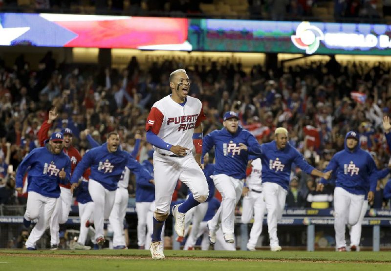 Puerto Rico’s Carlos Correa and teammates race to join the celebration after Correa scored on Eddie Rosario’s RBI single in the 11th inning to give Puerto Rico a 4-3 victory over the Netherlands at Dodger Stadium in Los Angeles. Puerto Rico advanced to its second consecutive World Baseball Classic championship game with the victory.