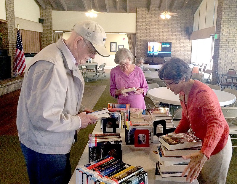 Lynn Atkins/The Weekly Vista Argie Willis, assistant director of the Bella Vista Library, right, sets up books for residents of Concordia as the traveling library program celebrates its first anniversary. Willis brings two cartloads of books to Concordia each visit but will also visit individuals with books they request.