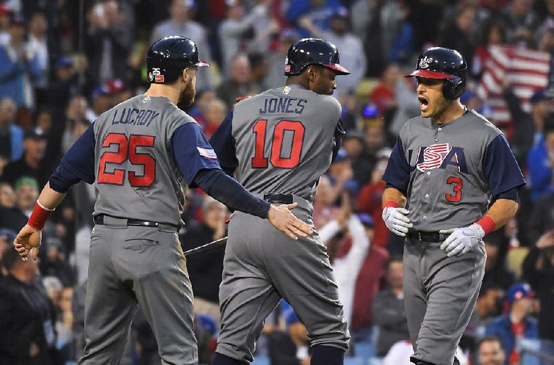 Ian Kinsler (3) is greeted by United States teammates Adam Jones (10) and Jonathan Lucroy after his two-run home run during the third inning of the Americans’ 8-0 victory over Puerto Rico on Wednesday night in the championship game of the World Baseball Classic at Dodger Stadium in Los Angeles.