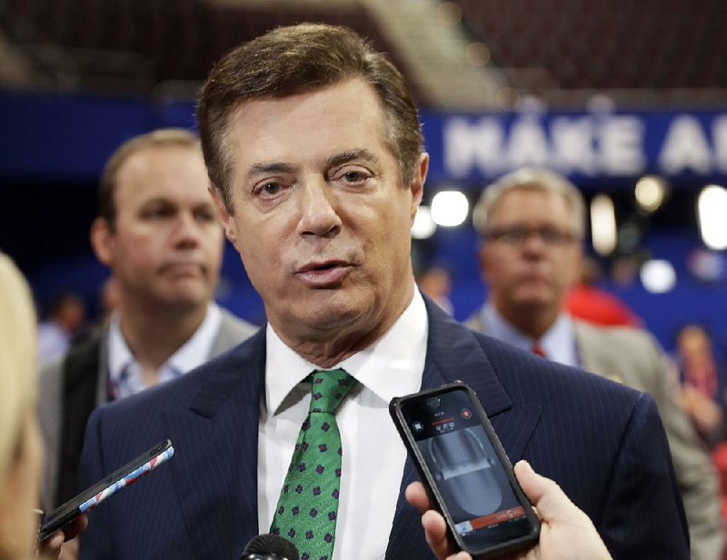 In this July 17, 2016 file photo, Trump campaign chairman Paul Manafort talks to reporters on the floor of the Republican National Convention at Quicken Loans Arena in Cleveland as Rick Gates listens at back left. 
