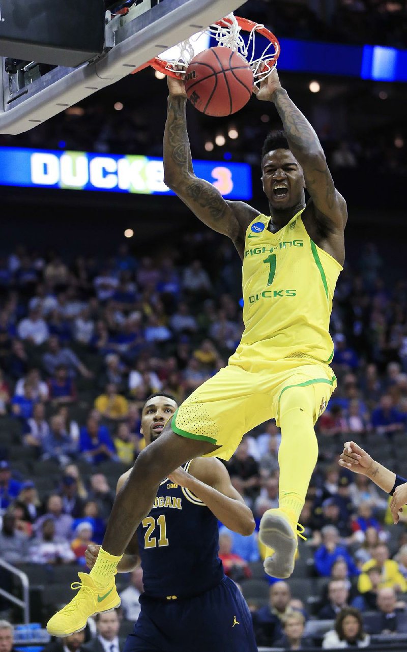 Oregon forward Jordan Bell dunks in front of Michigan guard Zak Irvin in a Midwest Regional semifi nal Thursday in Kansas City, Mo. Bell had 16 points and 13 rebounds as the Ducks held on to win 69-68 after Wolverines guard Derrick Walton missed a potential game-winning shot at the buzzer.