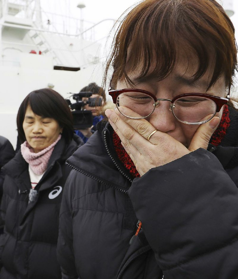 A relative of missing passengers of the sunken Sewol ferry cries Thursday as she watches workers lifting the boat in waters off Jindo, South Korea.