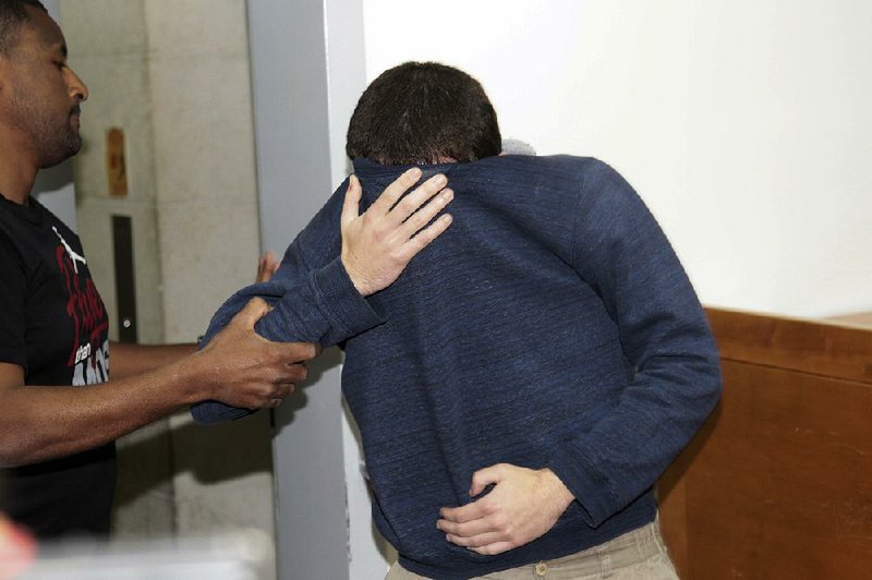 A 19-year-old U.S.-Israeli citizen covers his face during his court appearance Thursday in Rishon Lezion, Israel.