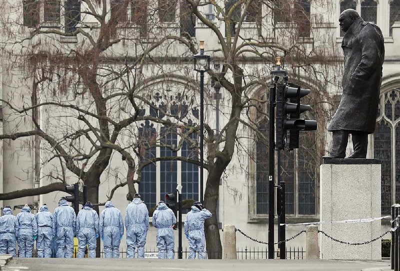 Police forensic officers work Thursday in Parliament Square, overseen by the statue of Winston Churchill outside the Houses of Parliament in London.