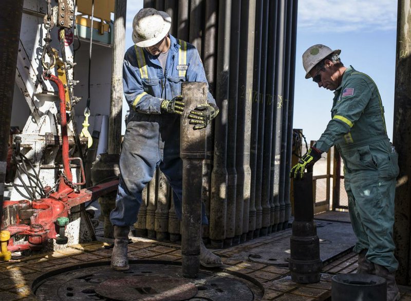 Precision Drilling oil rig operators install a bit guide on the floor of a Royal Dutch Shell oil rig near Mentone, Texas, in early March.
