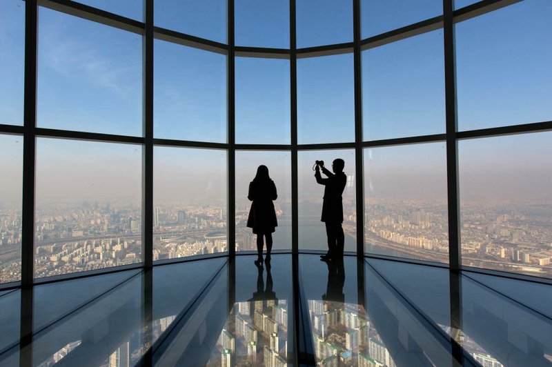 Visitors are silhouetted as they take photographs from the glass-bottomed observation deck at the Lotte Corp. World Tower in Seoul, South Korea, earlier this month.
