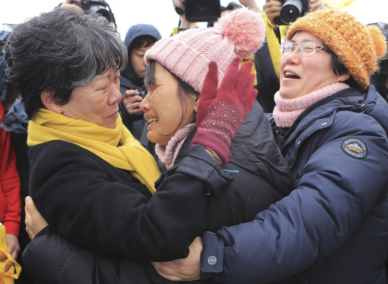 Relatives of victims of the 2014 Sewol ferry disaster comfort one another Saturday as they watch the sunken ship being pulled from the water off Jindo, South Korea.
