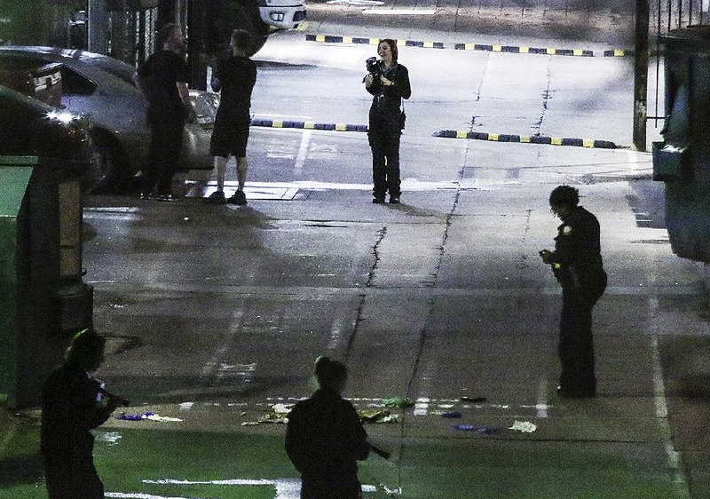 Little Rock police officers and crime scene investigators gather evidence at the site of a shooting early Sunday in downtown Little Rock where officers shot an unidentifi ed man who died a short time later.