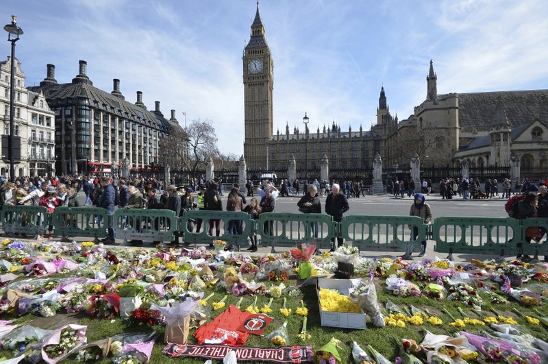 People look at tributes in Parliament Square, London, Saturday March 25, 2017, laid out for the victims of the Westminster attack on Wednesday. Khalid Masood killed four people and left more than two dozen hospitalized, including some with what have been described as catastrophic injuries. The Islamic State group claimed responsibility for the attack. 