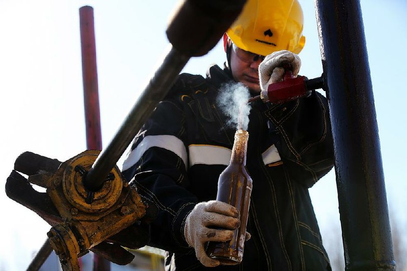 A worker collects a crude oil sample at a well operated by Rosneft in the Samotlor oilfi eld near Nizhnevartosk, Russia, on March 20. Russia joined OPEC in a January deal to cut output and strengthen prices.