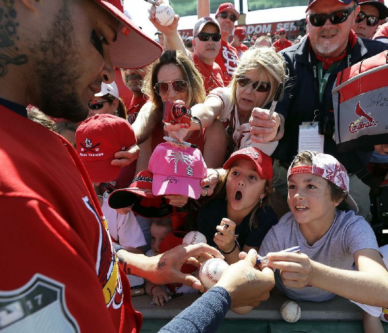 Marlee O'Fallon, 7, center, reacts as St. Louis Cardinals catcher Yadier Molina, left, signs her baseball before a spring training baseball game against the Miami Marlins Sunday, Feb. 26, 2017, in Jupiter, Fla. (AP Photo/David J. Phillip)