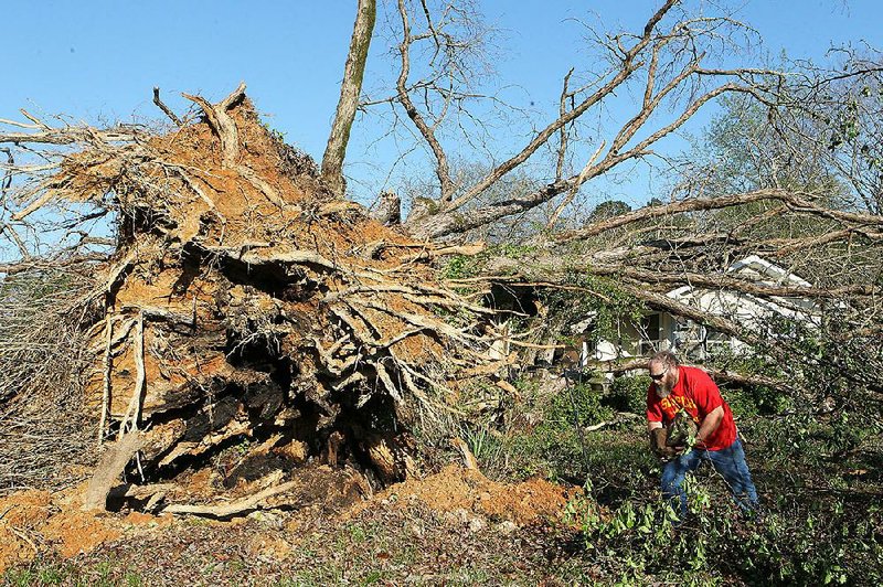 Shon Smith searches debris Sunday near a tree that fell on his house at 3725 Ten Mile Road in Saline County near the Garland County line. The National Weather Service said two tornadoes touched down in Saline County late Friday.