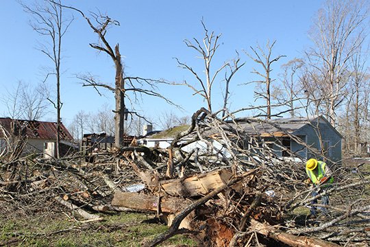 The Sentinel-Record/Richard Rasmussen AFTERMATH: An MDR Construction employee works on a downed power line near a house that was damaged during a tornado in the 3700 block of Ten Mile Road in Saline County near the Garland County line Sunday.