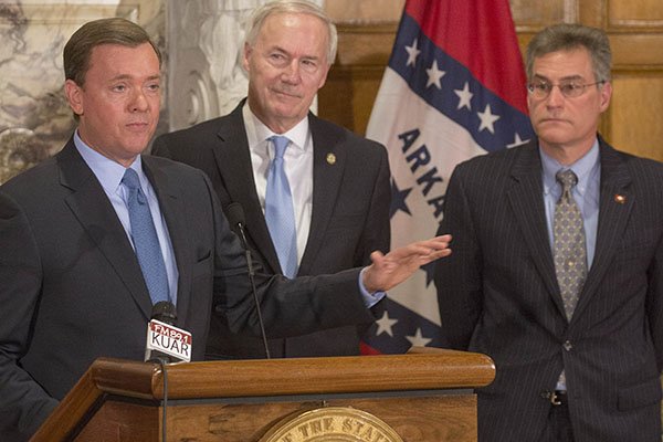 Gov. Asa Hutchinson, center, and Rep Charlie Collins, R-Fayetteville, right, listen to comments from NRA Institute for Legislative Action executive director Chris Cox, left, about the benifits of HB 1249 which Hutchinson signed into law Wednesday. The bill expands the places concealed-carry permit holders can take their guns in Arkansas.
