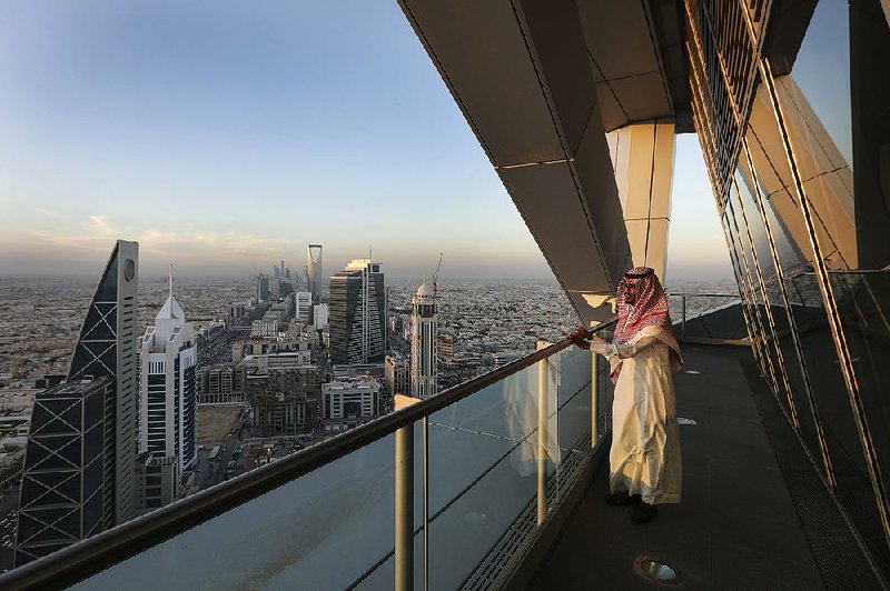 An employee looks out from the 32nd-floor viewing platform of the Al Faisaliah Tower in Riyadh, Saudi Arabia, in December. The government-owned national oil company Aramco is trying to reform and diversify its oil-dependent economy. 