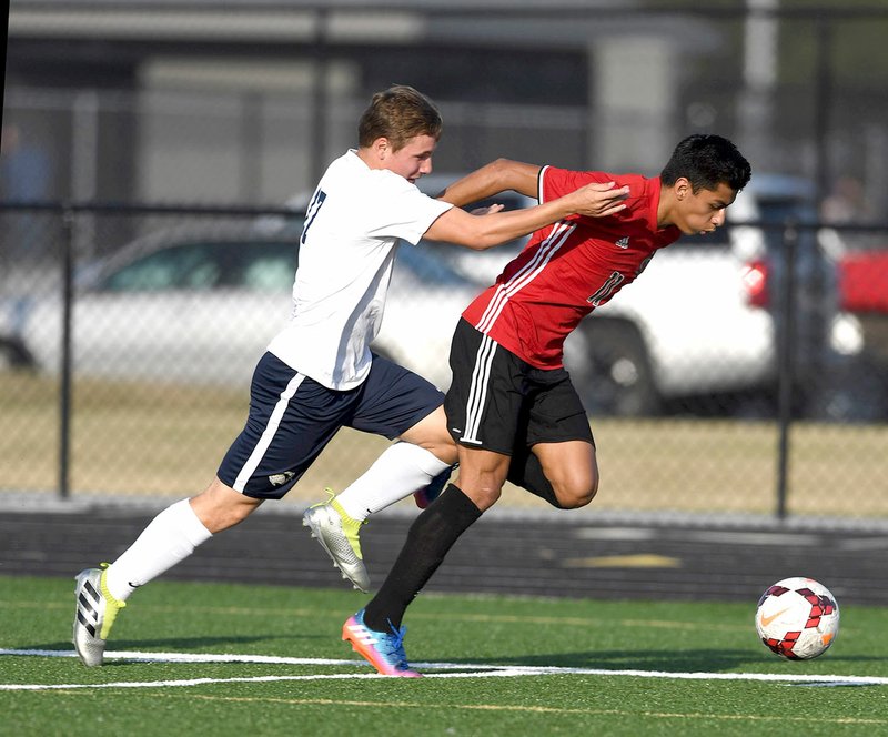 Springdale High’s Salvador Gonzalez (right) races Tanner Travis (17) of Bentonville West for the ball Tuesday in Centerton.