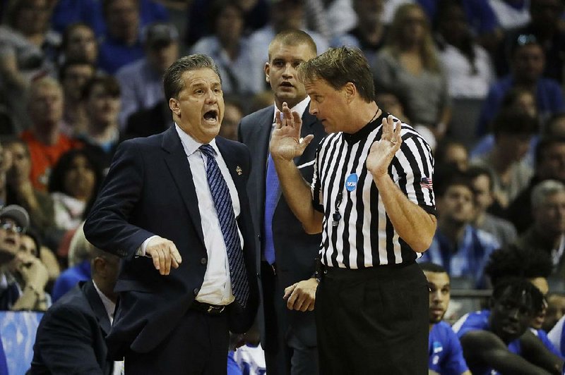 Referee John Higgins (right), shown with Kentucky Coach John Calipari during Sunday’s NCAA South Regional final against North Carolina, has received nonstop phone calls and even death threats from Kentucky fans since the game.