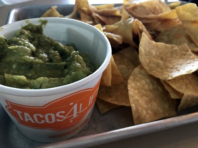 Dishes, such as guacamole and chips, are served on metal trays at fast-casual Tacos 4 Life in Little Rock. 