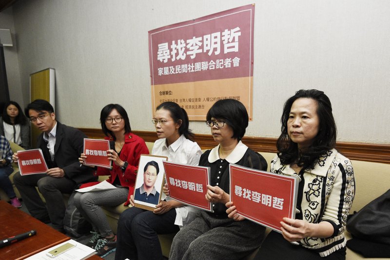 In this photo taken Friday, March 24, 2017, Lee Ching-yu, third from right holds up a photo of her missing husband and Taiwanese pro-democracy activist Lee Ming-che during a press conference with other representatives of non-governmental organizations calling for help to find his whereabouts in Taipei, Taiwan. 