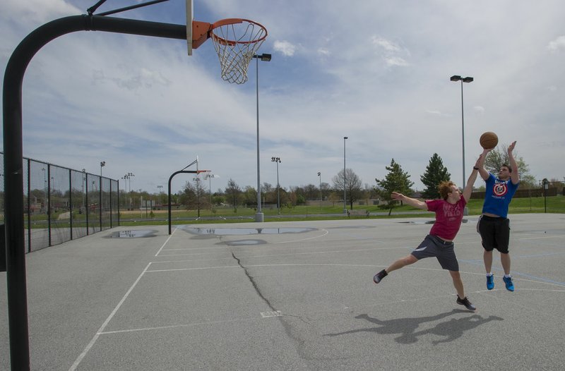Zach Sjogren (right) of Bella Vista and Austin Walker of Rogers play basketball Wednesday at Memorial Park in Bentonville. The pair met to get some exercise and enjoy the mild weather in Northwest Arkansas. An annual report again ranked Benton County as the state’s healthiest.