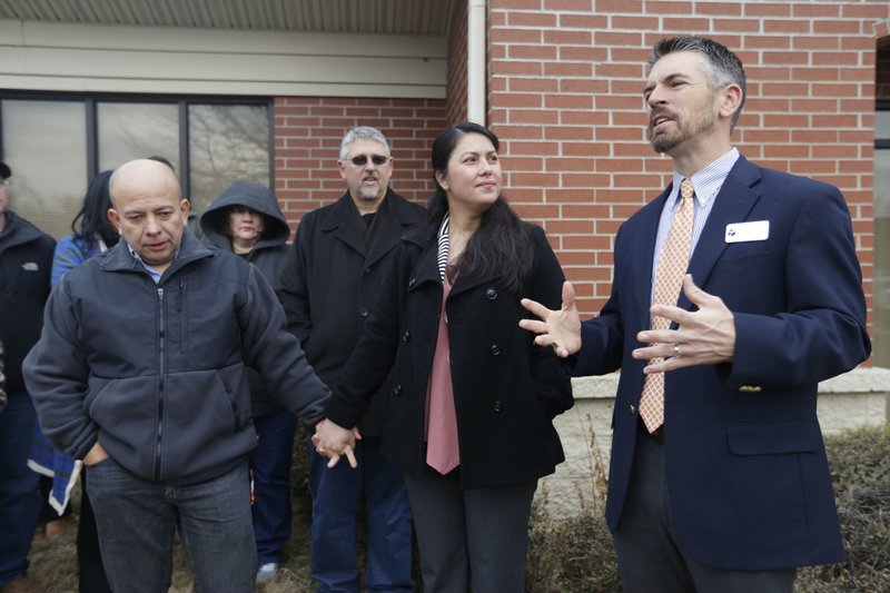 Jose and Amanda Aristondo hold hands and listen as Pastor Mark Snodgrass (right) speaks March 14 outside the U.S. Immigration and Customs Enforcement office in Fayetteville.