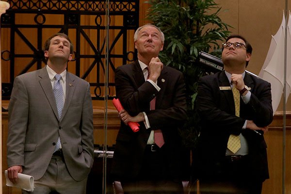 Gov. Asa Hutchinson, center, and two member of his staff watch a television monitor from a VIP gallery above the house floor as Rep. Charles Collins, R-Fayetteville, presents SB724 (gun bill) on the floor Thursday, March 30, 2017, at the State Capitol in Little Rock.
