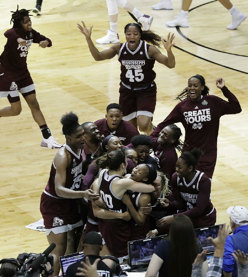 Mississippi State’s Morgan William is mobbed by her teammates after she hit the game-winning shot at the buzzer to give the Bulldogs a 66-64 overtime victory over Connecticut at the Final Four in. Dallas on Friday night. The victory ended UConn’s record 111-game winning streak.