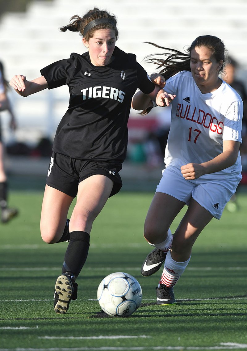 Bentonville High’s Emma Welch (left) keeps the ball away from Springdale High’s Nayeli Contreras on Friday at Jarrell Williams Bulldog Stadium in Springdale.
