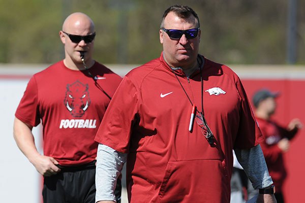 Arkansas coach Bret Bielema (right) watches Saturday, April 1, 2017, as head strength and conditioning coach Ben Herbert leads warmup drills during practice at the university practice field in Fayetteville.